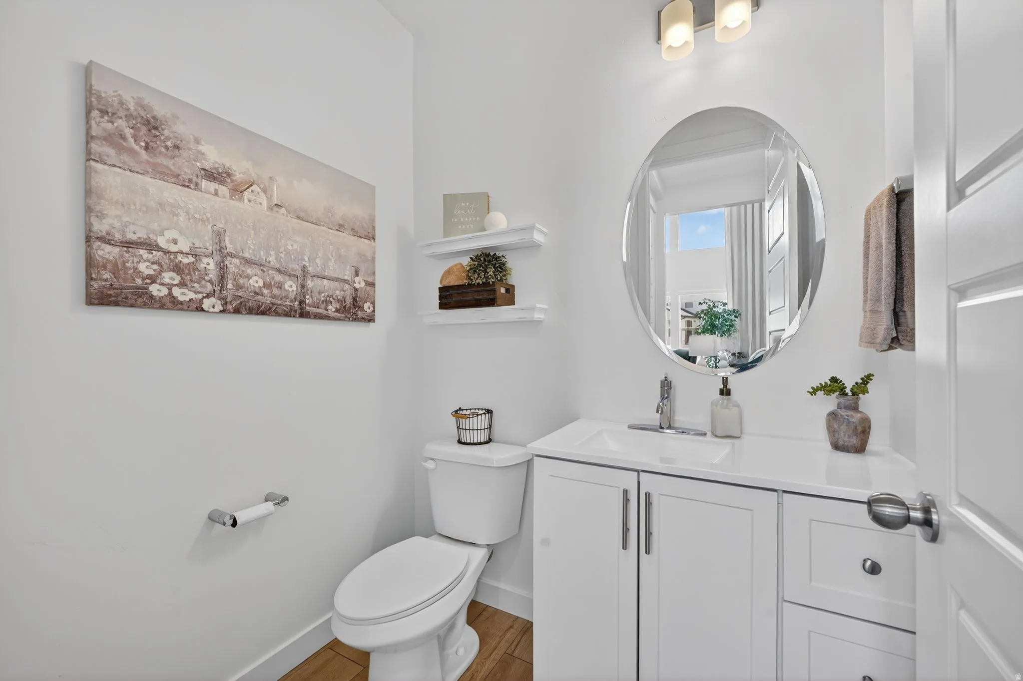 Bathroom featuring a white vanity with integrated sink, chrome faucet, oval mirror, and overhead lighting