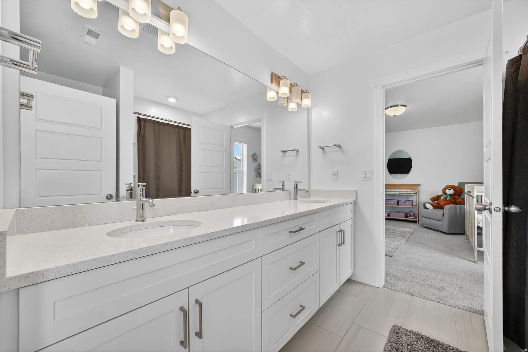 Double vanity with white cabinetry, light-toned countertops, and brushed nickel hardware