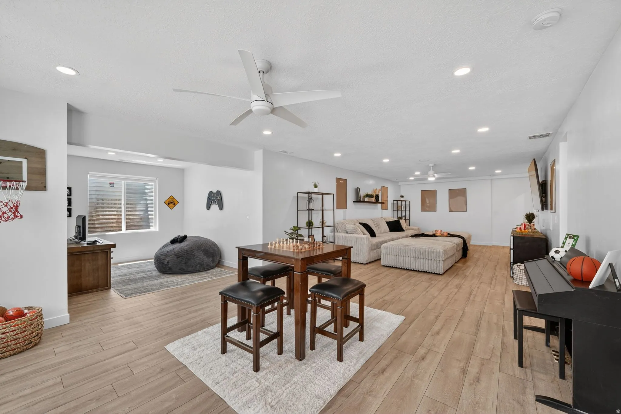 Spacious open-concept room featuring wood-finish flooring, recessed lighting, and a modern ceiling fan