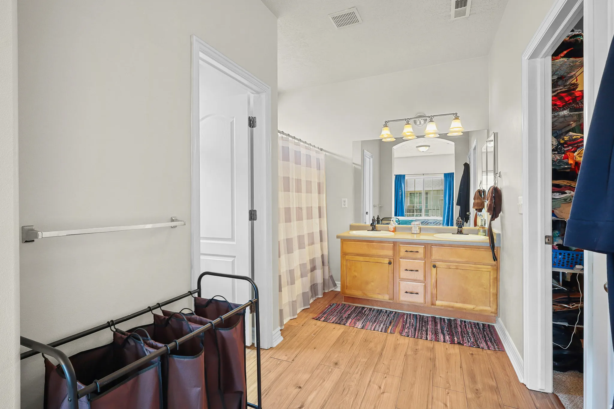 Bathroom featuring a double vanity with light wood cabinetry, dual undermount sinks, and a shared mirror