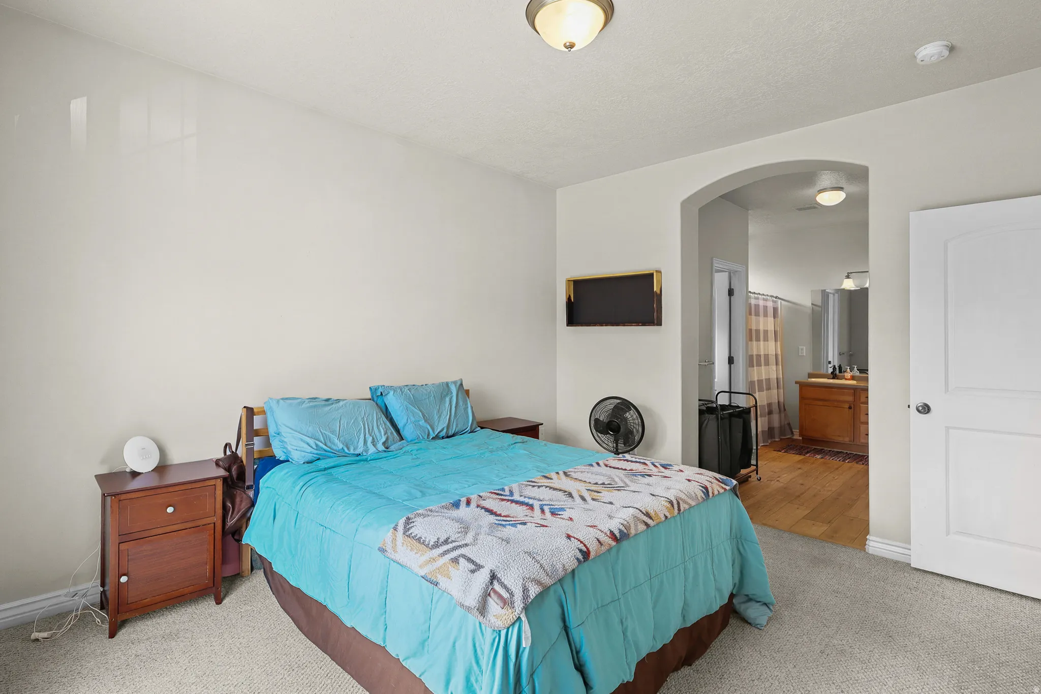 Carpeted bedroom featuring neutral wall tones, an arched doorway, and white trim