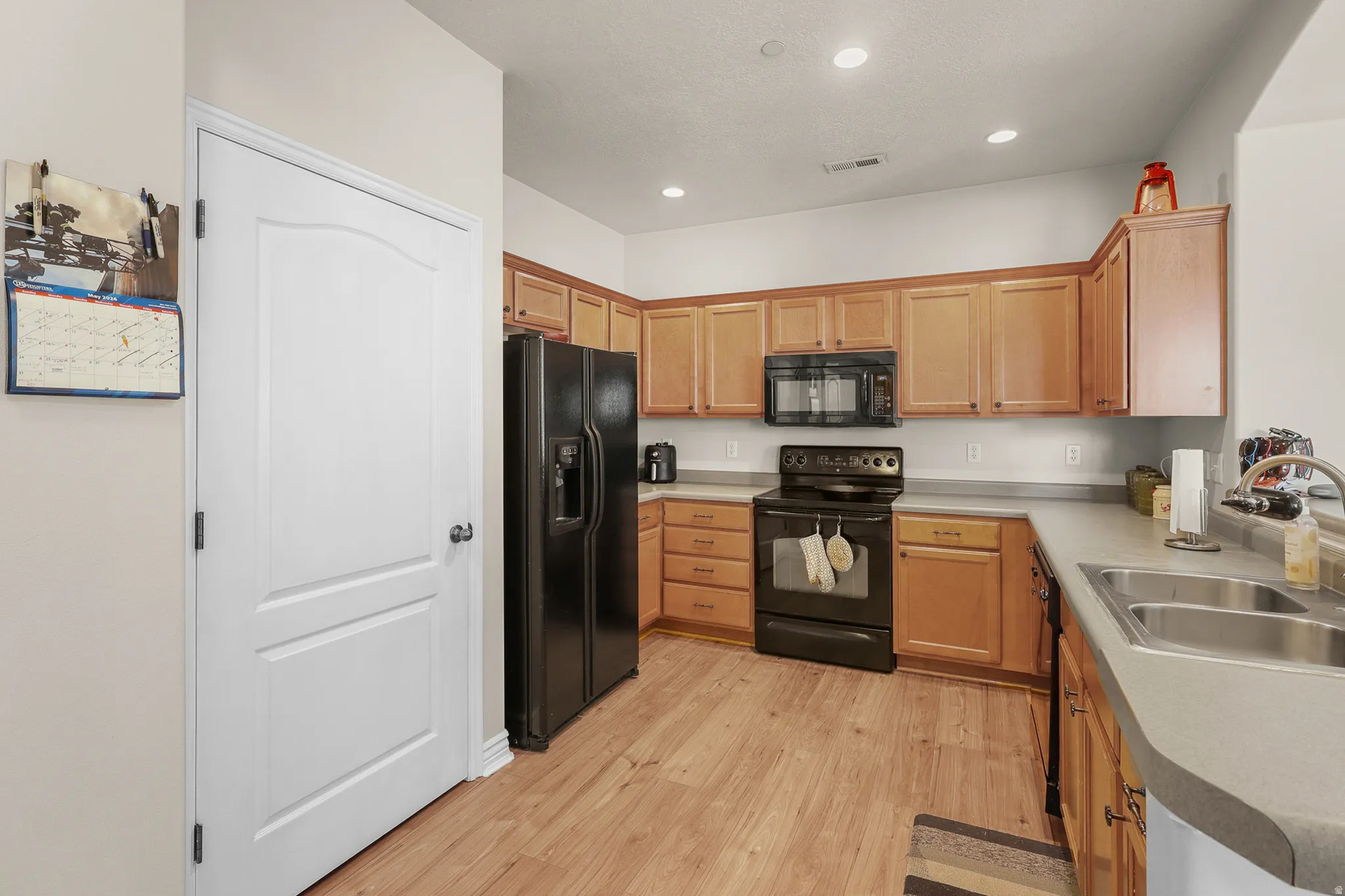Kitchen featuring wood-finish flooring, recessed lighting, and light wood cabinetry with dark hardware