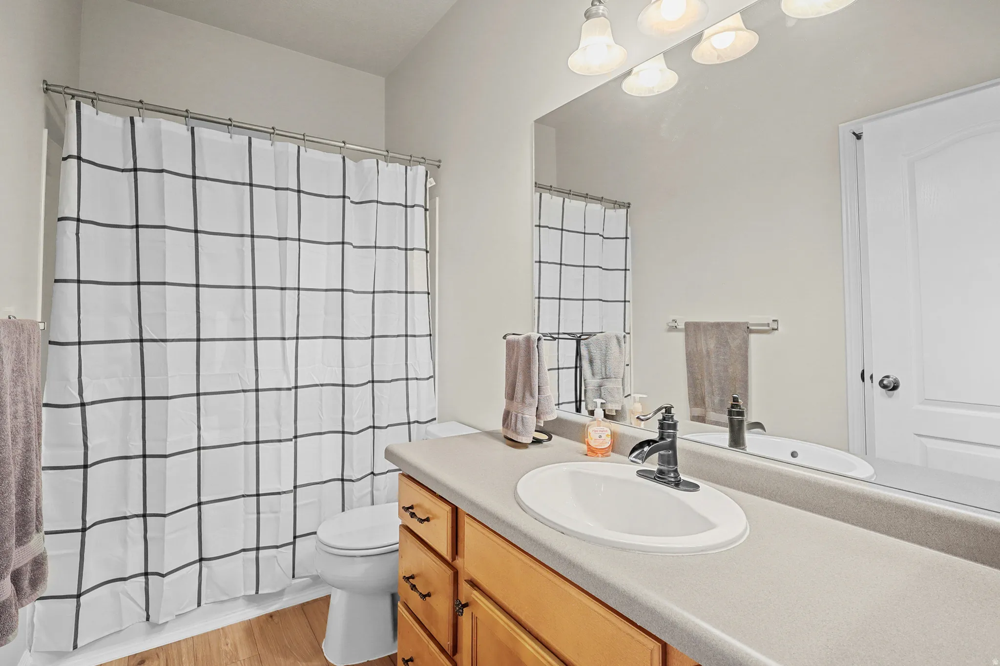 Bathroom vanity with wood-finish cabinetry, integrated sink, and gray countertop