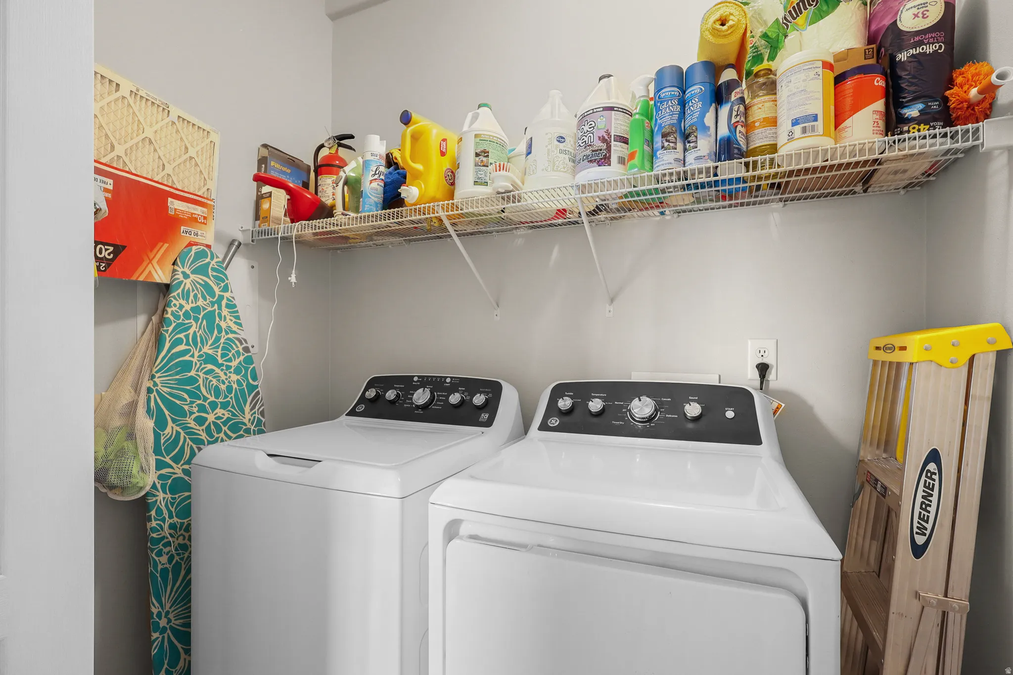 Dedicated laundry area featuring a washer and dryer, integrated shelving for storage, and a power outlet