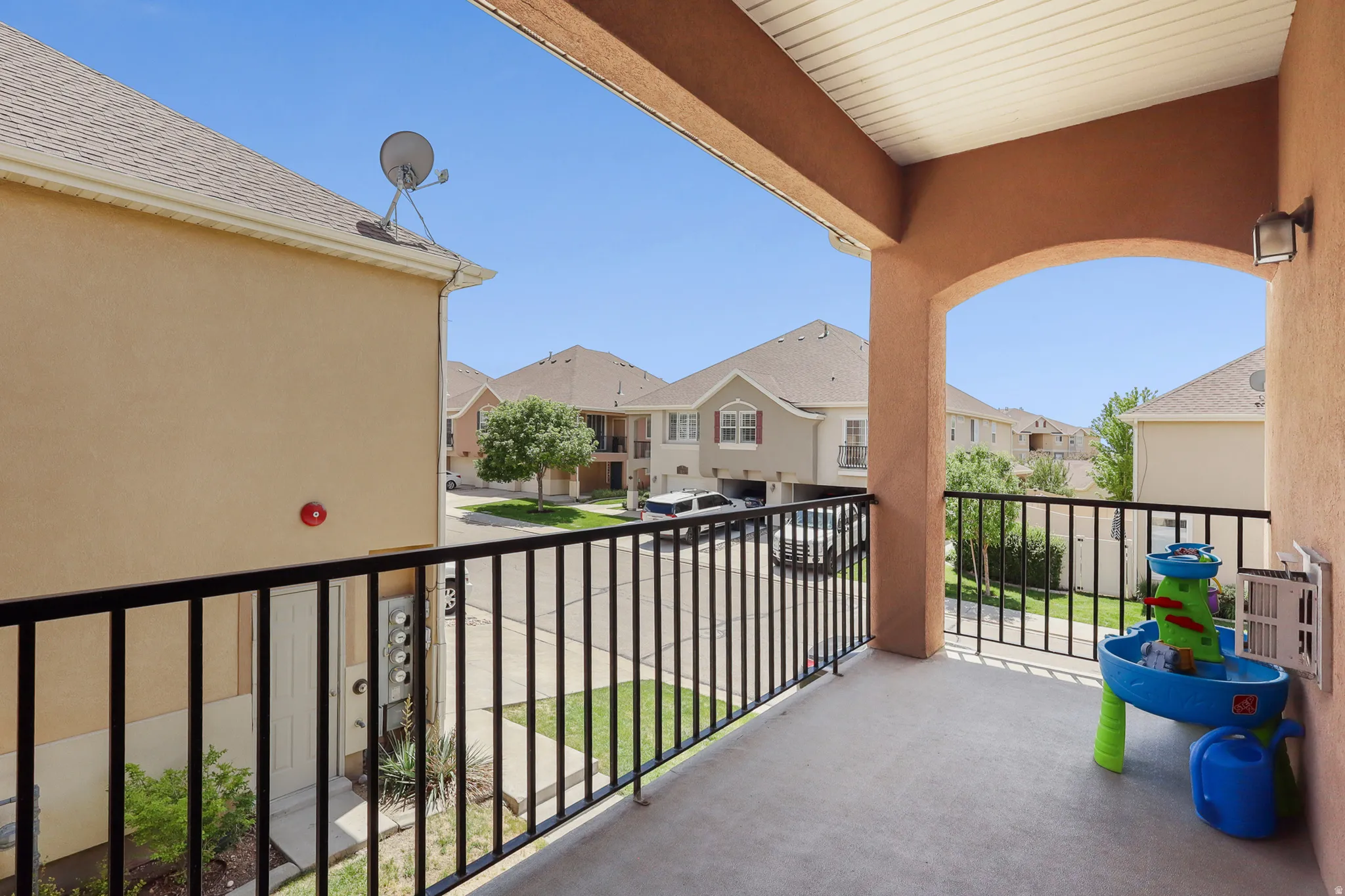 Covered balcony with arched entryway, stucco exterior, and black metal railing