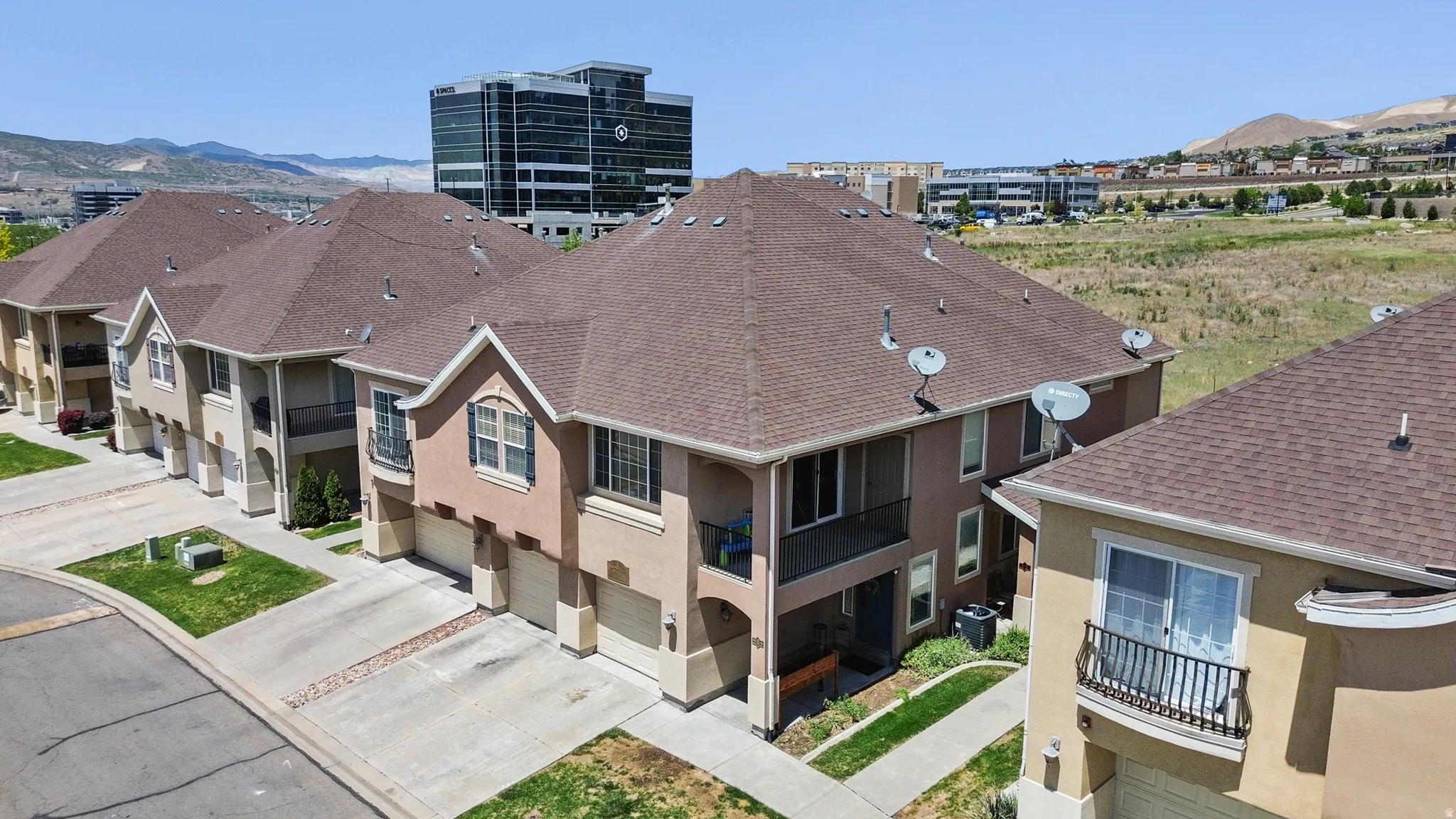 Row of multi-story townhomes featuring stucco exteriors and gabled roofs