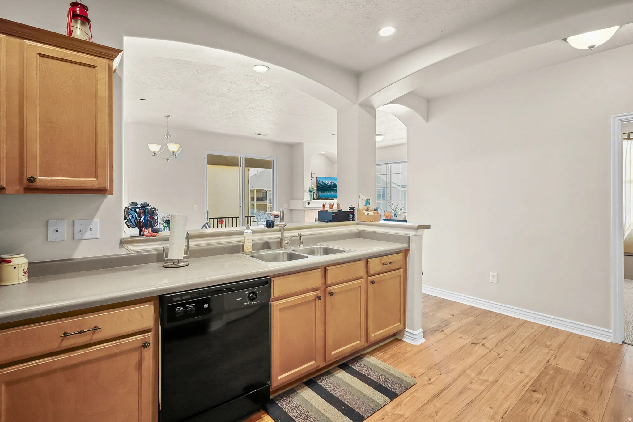 Kitchen featuring light wood cabinetry, a black dishwasher, and a double basin sink