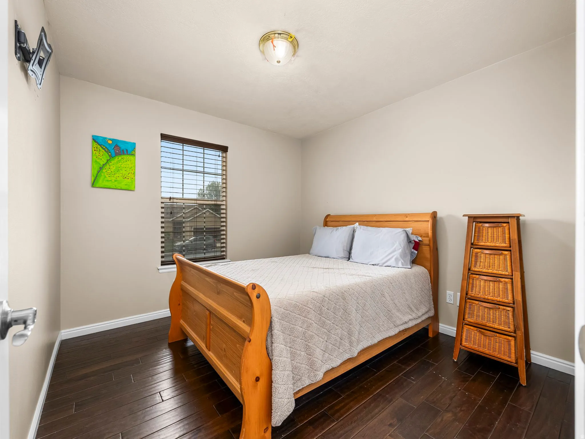 Bedroom featuring dark wood-finish flooring, a single window with blinds, and neutral wall tones
