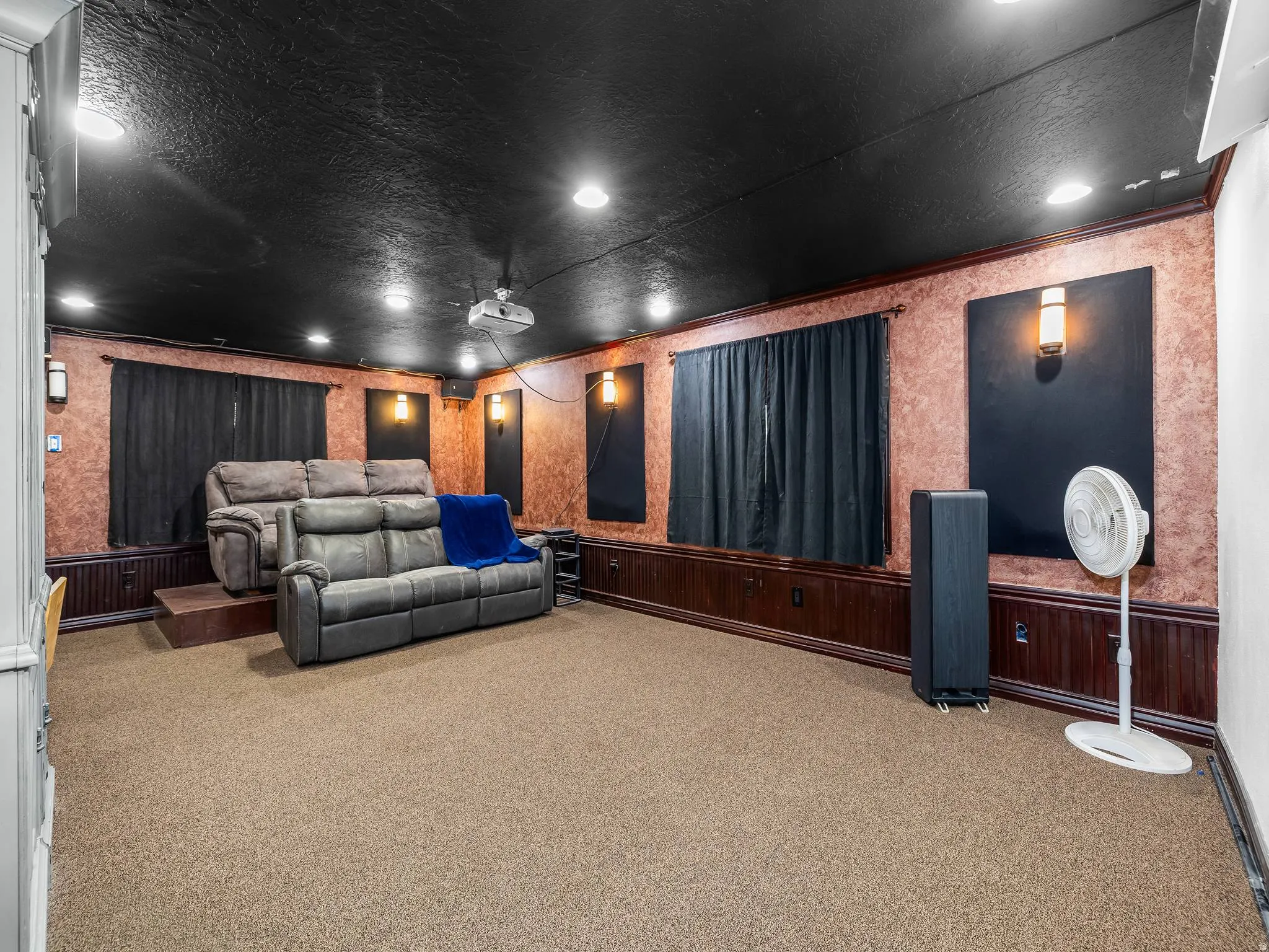 Dedicated media room featuring recessed lighting, a dark ceiling, textured walls, and a projector