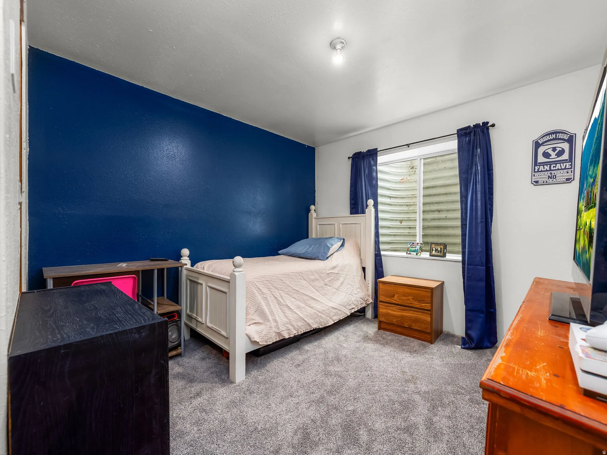 Room featuring gray carpeting and a prominent blue accent wall