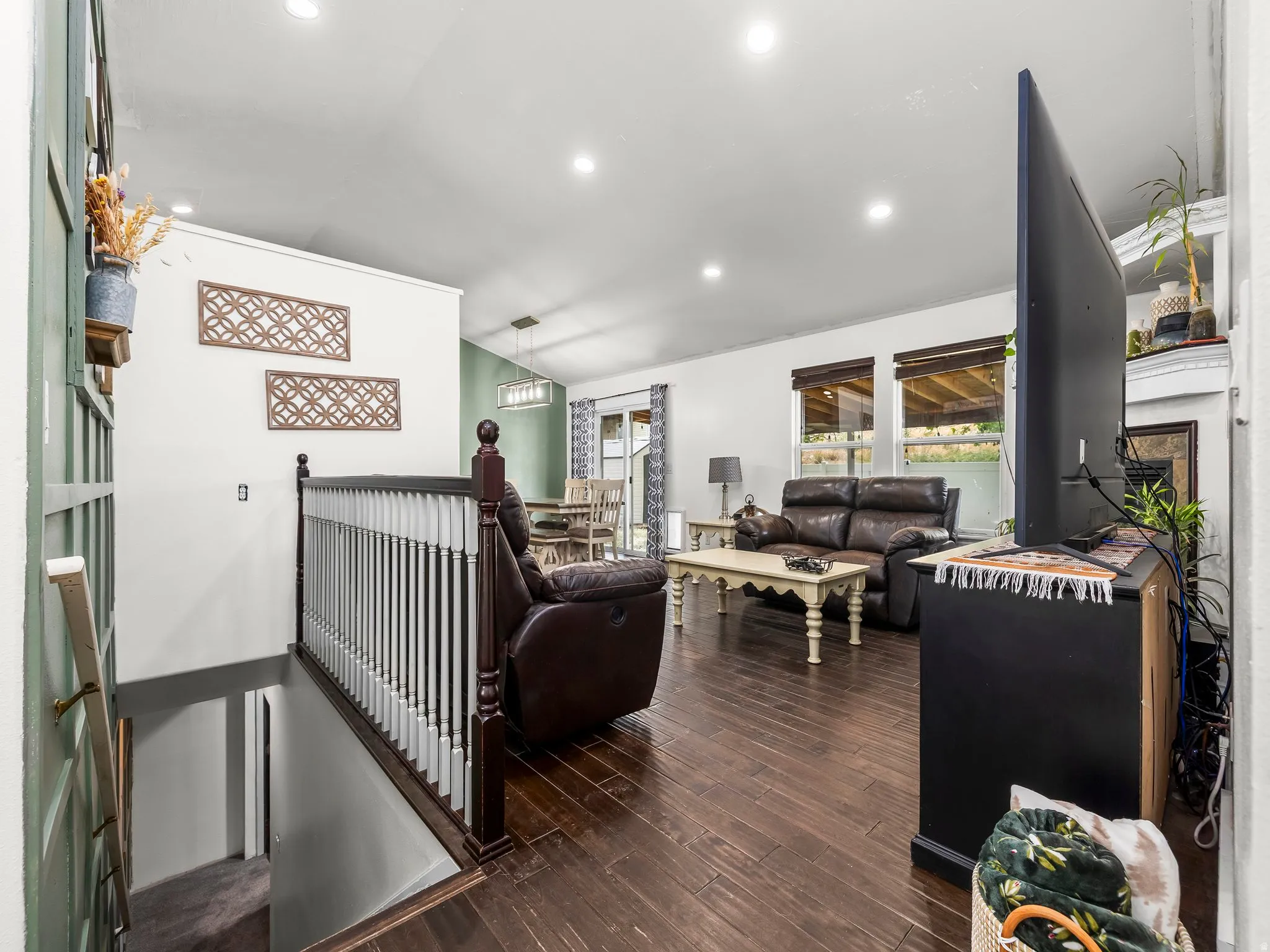 Open-concept living space featuring wood-finish flooring, recessed lighting, and a white baluster railing