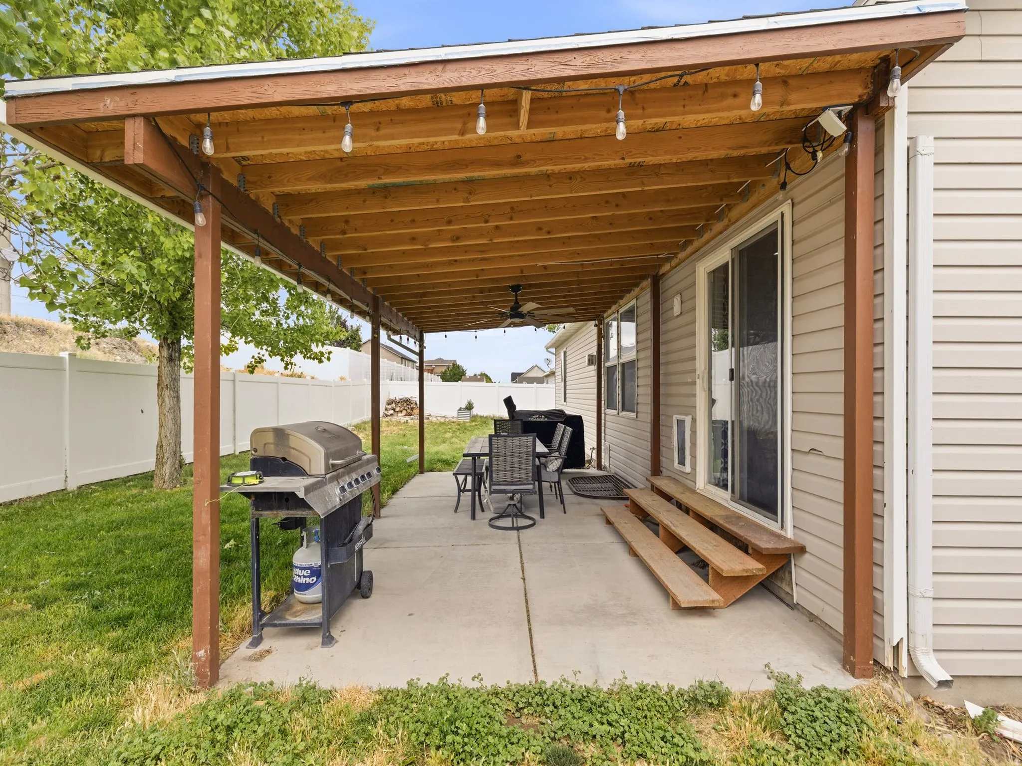 Covered concrete patio featuring string lighting, wood-finish ceiling, and a sliding glass door