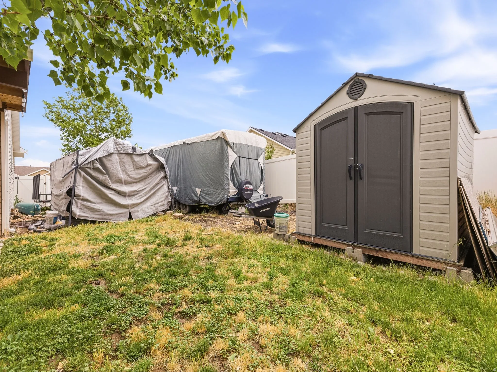 Plastic shed with double dark gray doors, a neutral-toned siding, and a gabled roofline