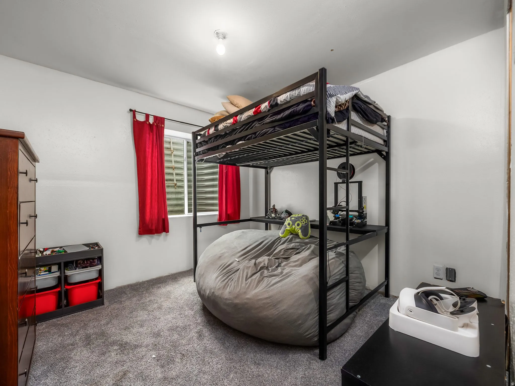 Carpeted room featuring a window with horizontal blinds and red drapes, a built-in light fixture, and white wall finishes