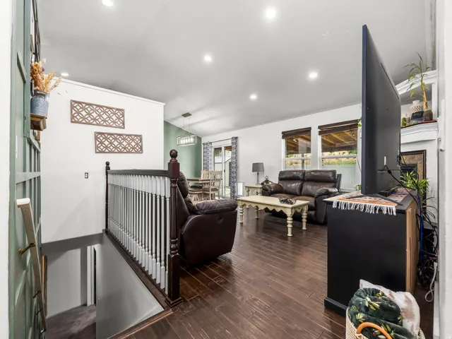 Open-concept living space featuring wood-finish flooring, recessed lighting, and a white baluster railing