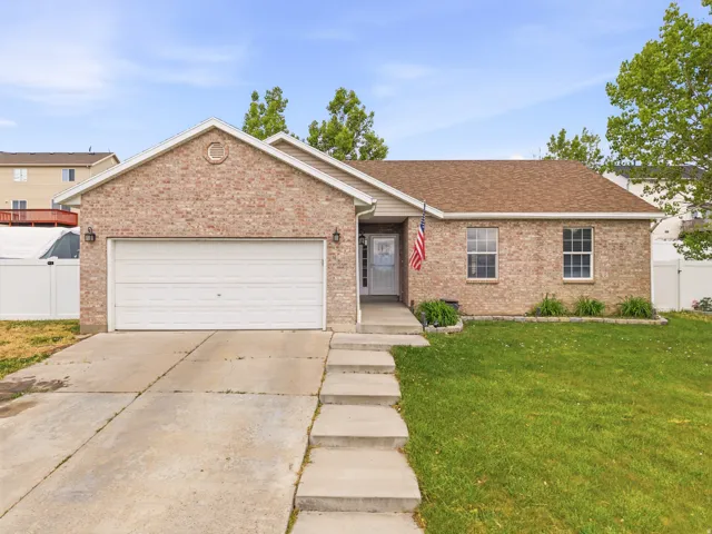 Brick exterior featuring a two-car garage, concrete driveway, and a front walkway leading to the entry