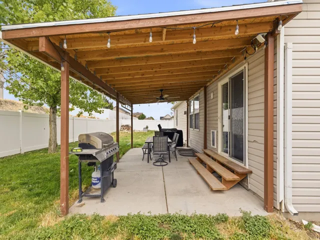 Covered concrete patio featuring string lighting, wood-finish ceiling, and a sliding glass door