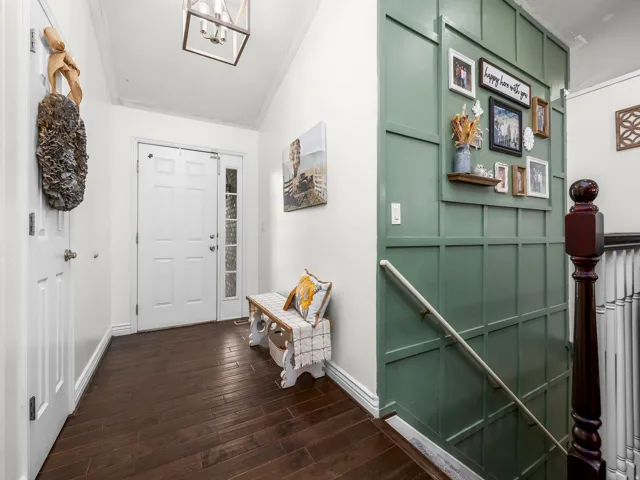 Entryway featuring dark wood-finish flooring, a white paneled door with frosted glass sidelight, a decorative wall paneling in a green hue, and a square ceiling light fixture