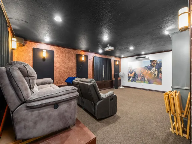 Dedicated media room featuring a large projection screen, recessed lighting, and wall-mounted sconces