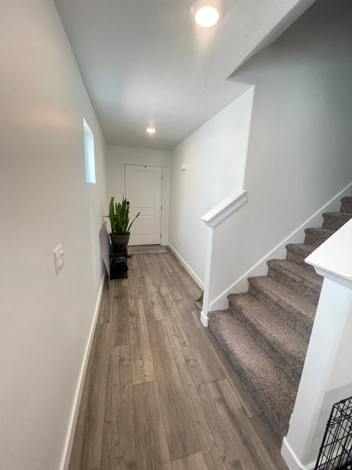 Hallway featuring wood-finish flooring and a carpeted staircase