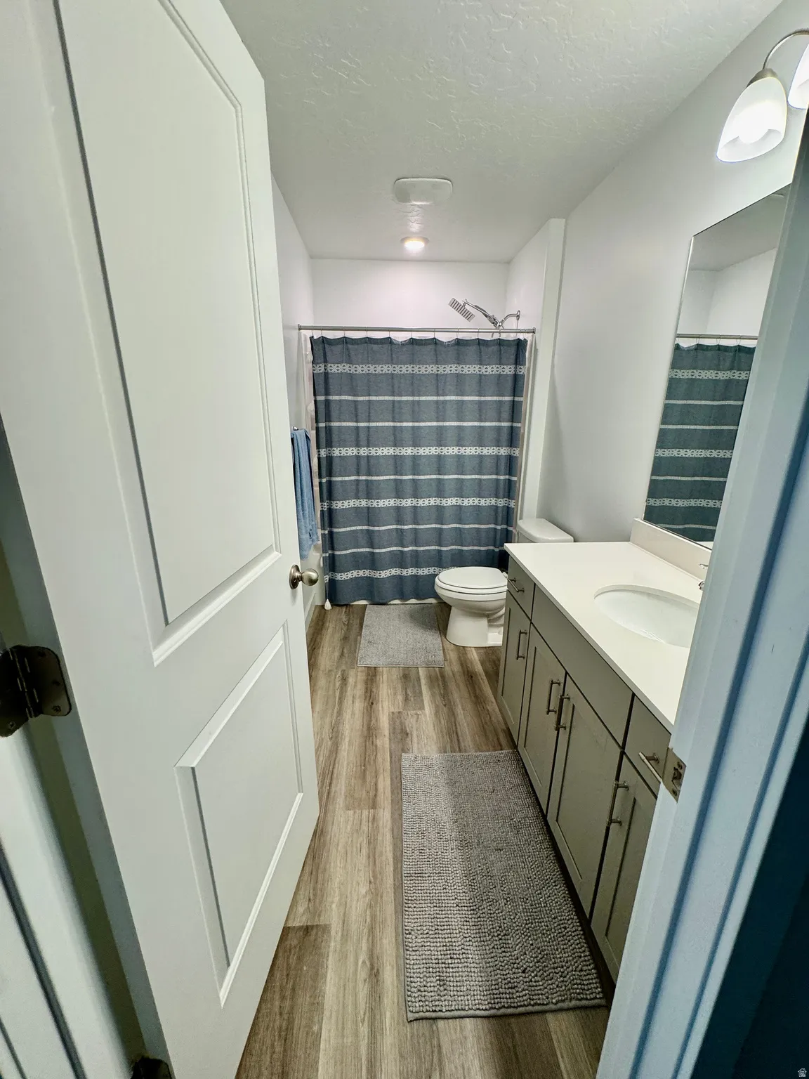Full bathroom featuring wood-finish flooring, a white vanity with integrated sink, and a combination shower/tub