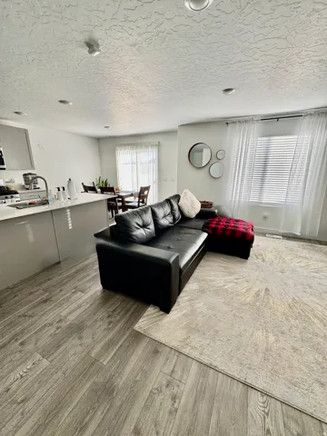 Open-concept living area with wood-finish flooring, recessed lighting, and a neutral color palette