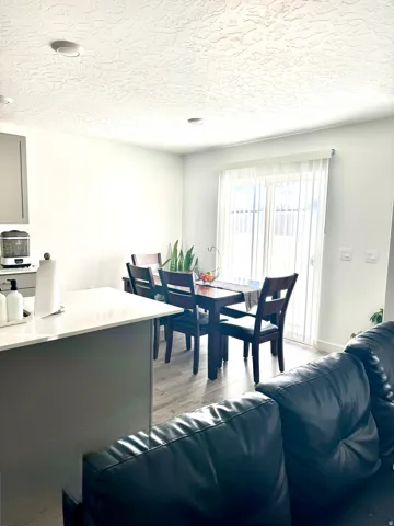 Dining area featuring a sliding glass door with vertical blinds, wood-finish flooring, and recessed ceiling lighting