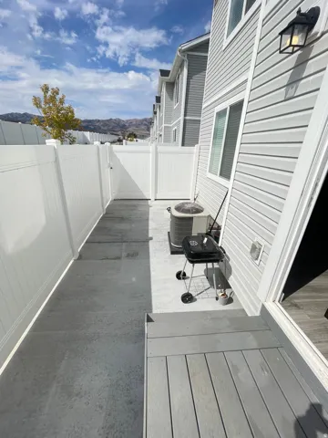Enclosed patio area featuring a white privacy fence with gate, concrete paving, and a grey composite deck with steps