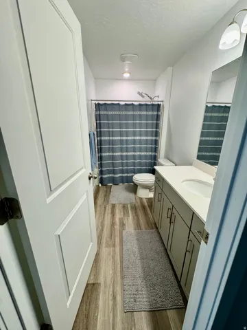Full bathroom featuring wood-finish flooring, a white vanity with integrated sink, and a combination shower/tub