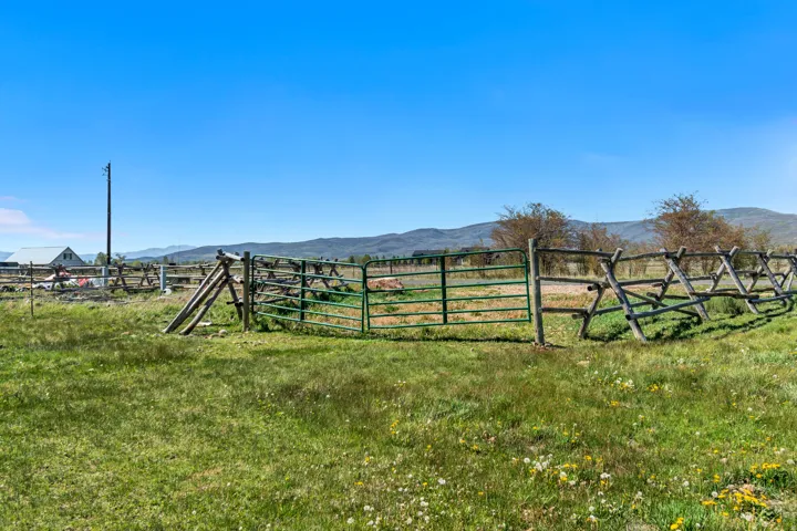 Expansive green field with a wooden split-rail fence and a green metal gate