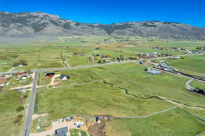 Expansive green landscape featuring distant mountains, multiple residential structures, and meandering natural waterways