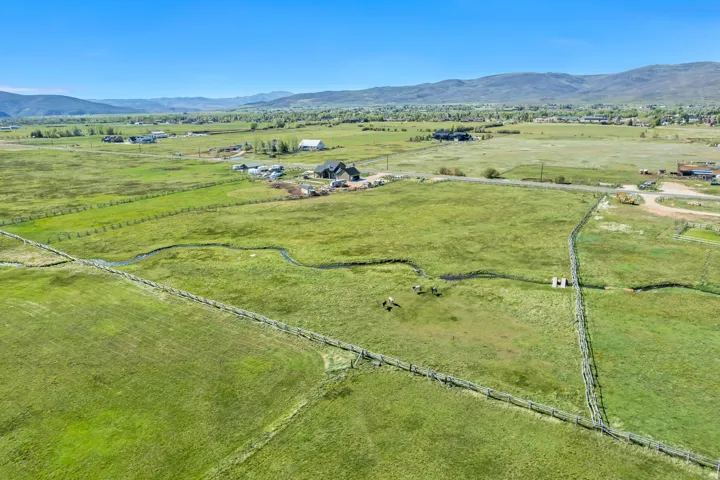 Expansive green acreage with distant mountain ranges and a winding natural waterway