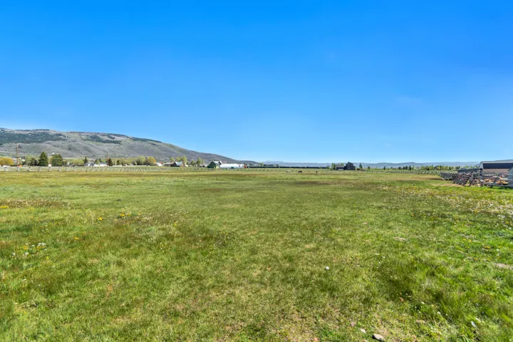 Expansive grassy field with distant mountainous terrain, offering open skies and a broad horizon