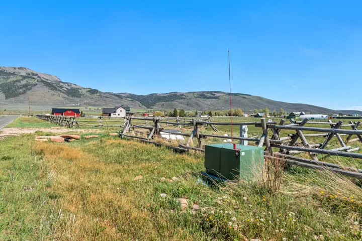Expansive land parcel featuring a split rail fence and a vibrant green utility box