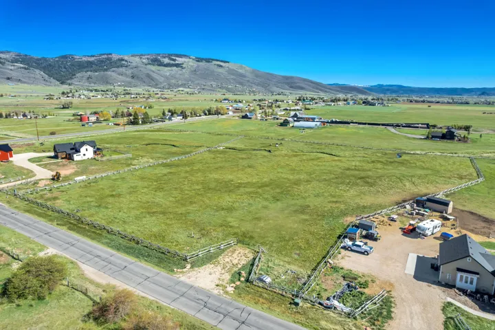 Expansive fenced acreage featuring a paved road frontage and distant mountain backdrop