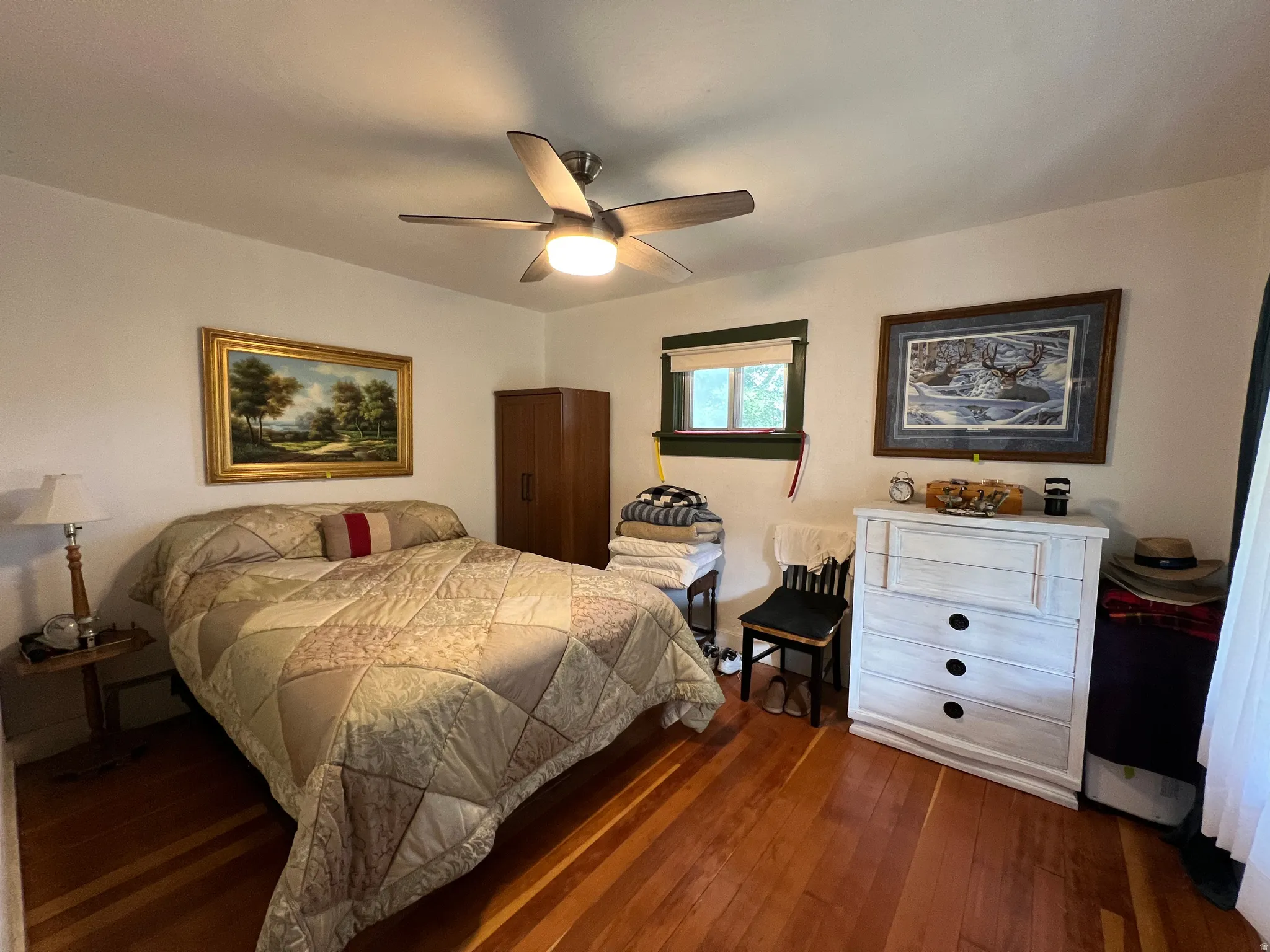 Hardwood flooring throughout, ceiling fan with integrated lighting, and a window with trim