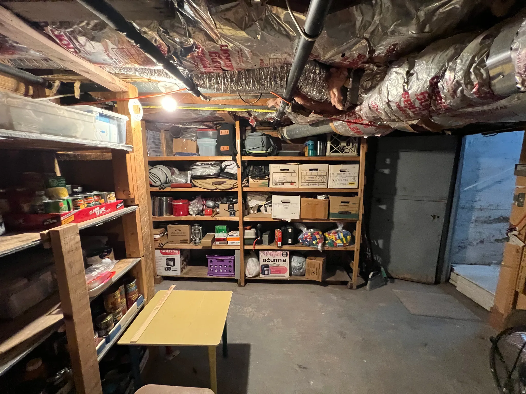 Unfinished basement space featuring exposed wood joists and utility piping