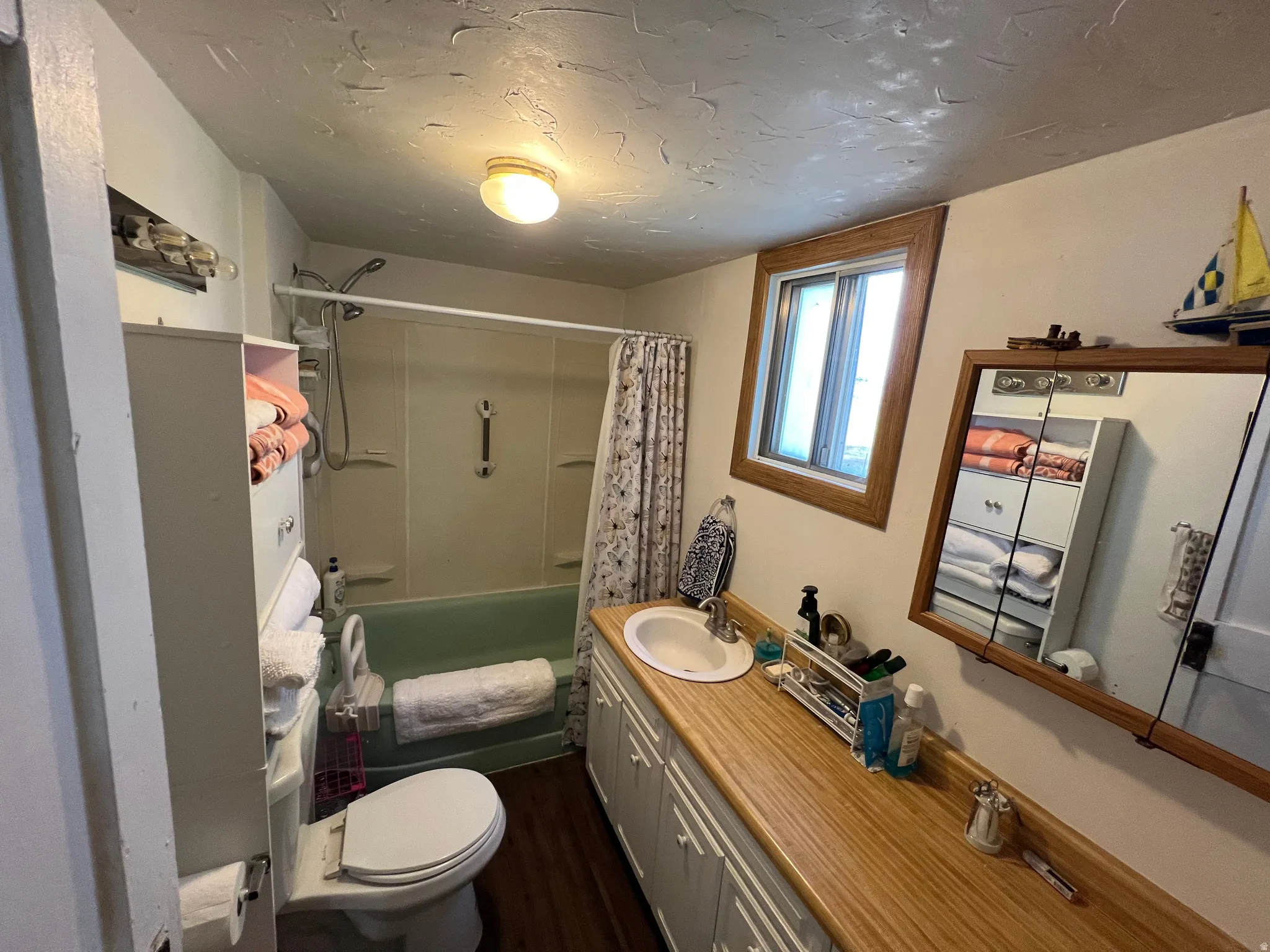 Bathroom featuring a wood-finish vanity countertop, white cabinetry with silver-tone hardware, and a single basin sink