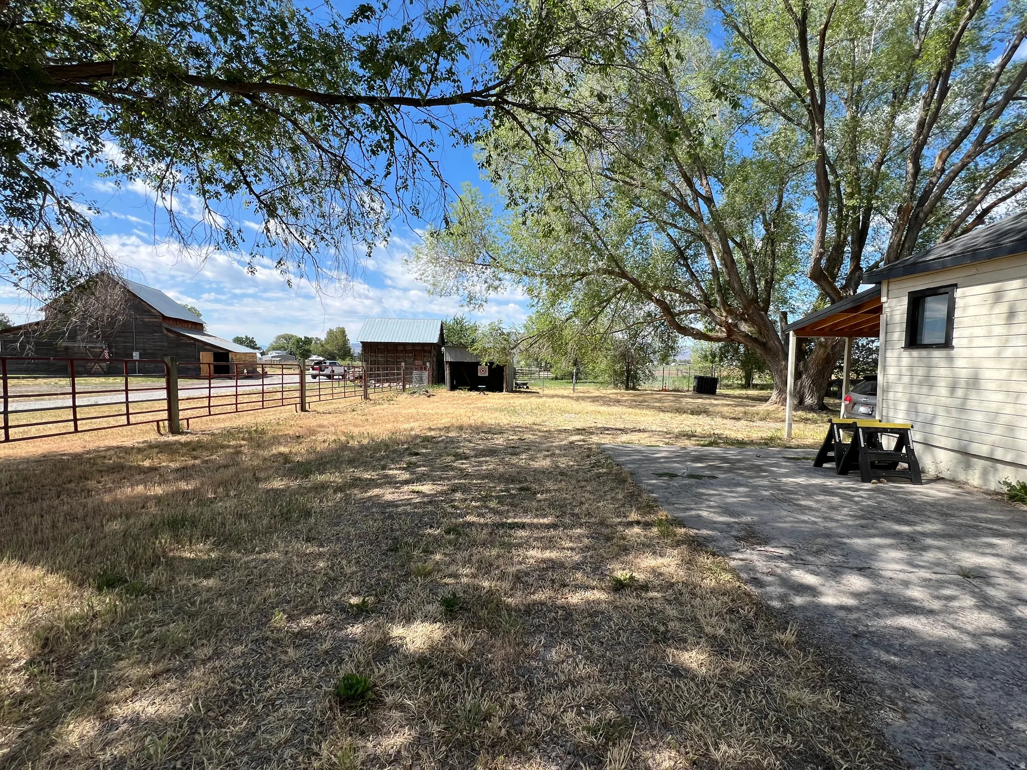 Expansive property featuring a paved patio, a covered porch, and mature trees