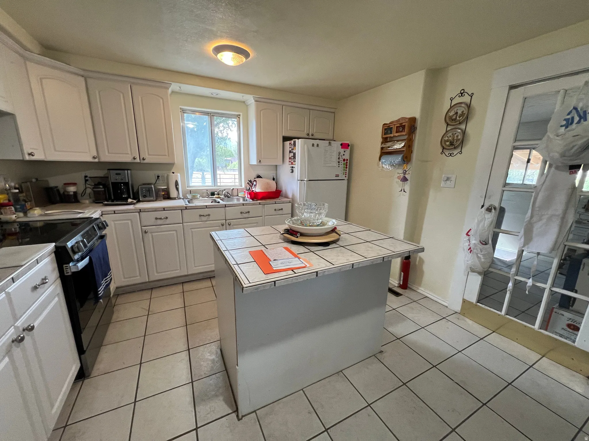 Kitchen featuring white cabinetry, tile countertops, tile flooring, and a central island with a tile surface