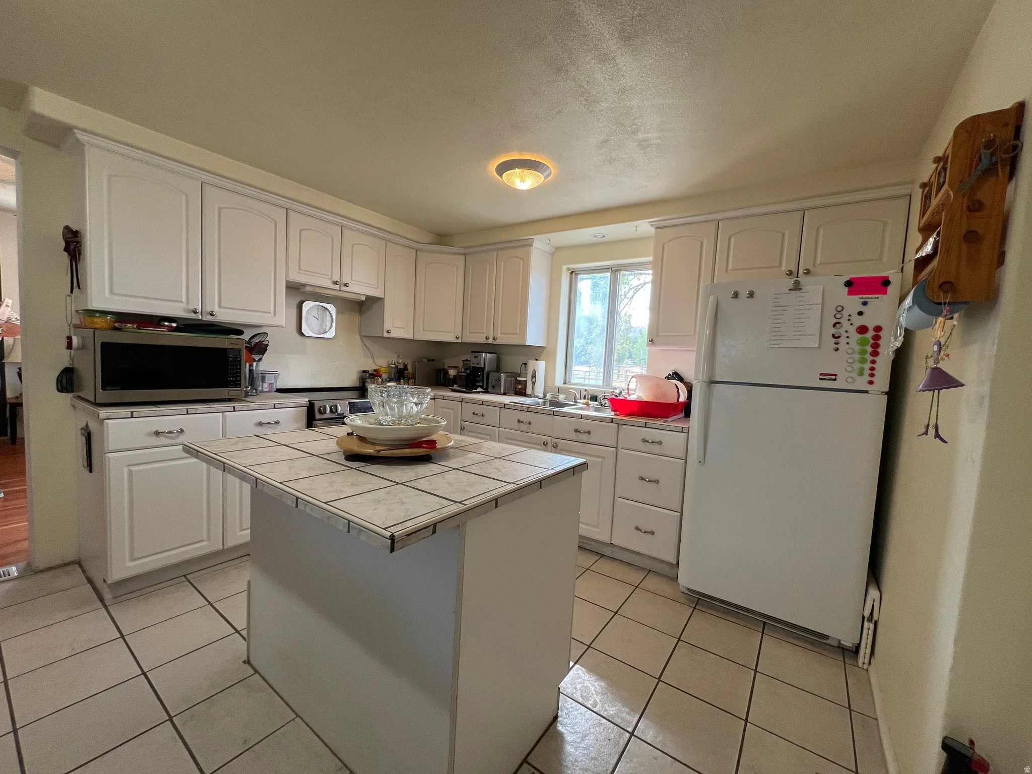 Kitchen featuring white cabinetry, tile countertops, an island with a tiled surface, tile flooring, and a recessed ceiling light fixture