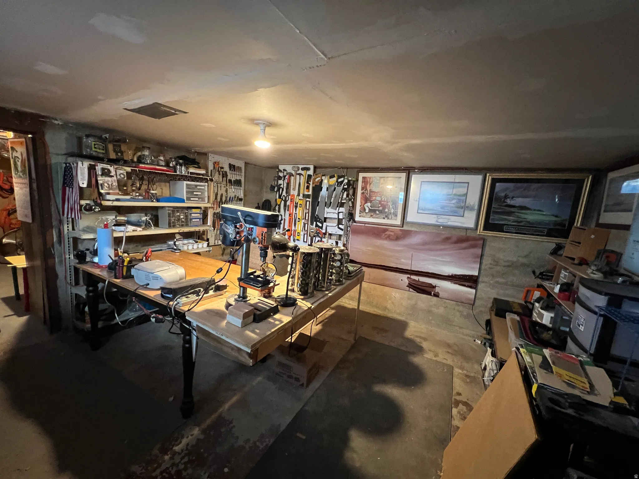 Utility room with concrete flooring and exposed ceiling, featuring a central workbench