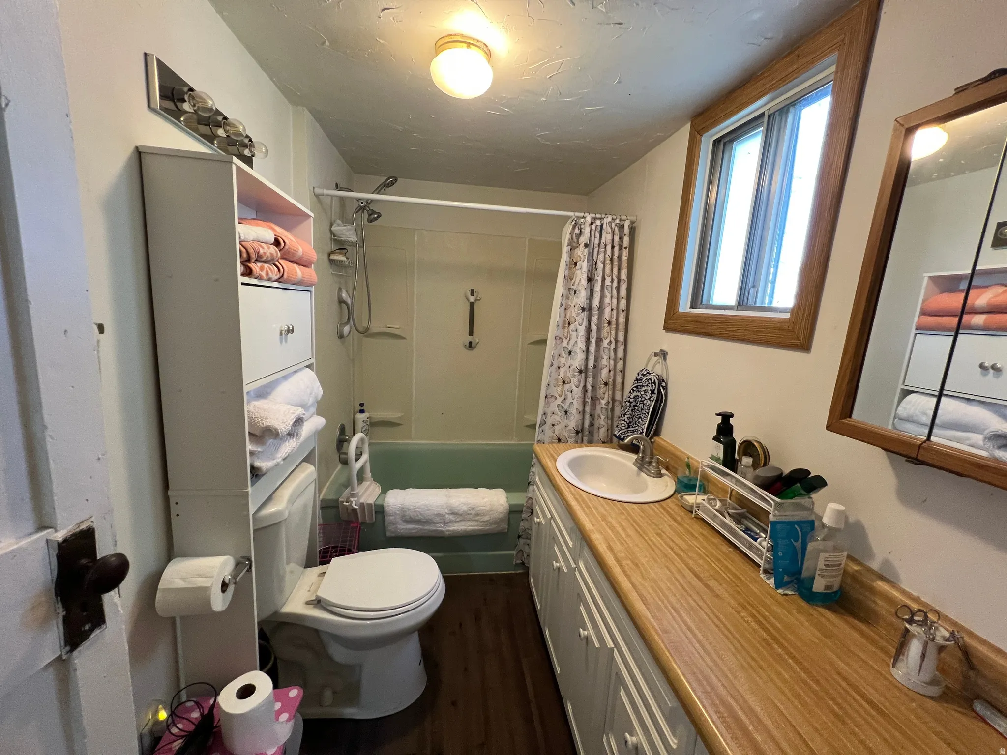 Full bathroom featuring a wood-finish vanity countertop, white cabinetry, and a built-in medicine cabinet with a wood-frame mirror