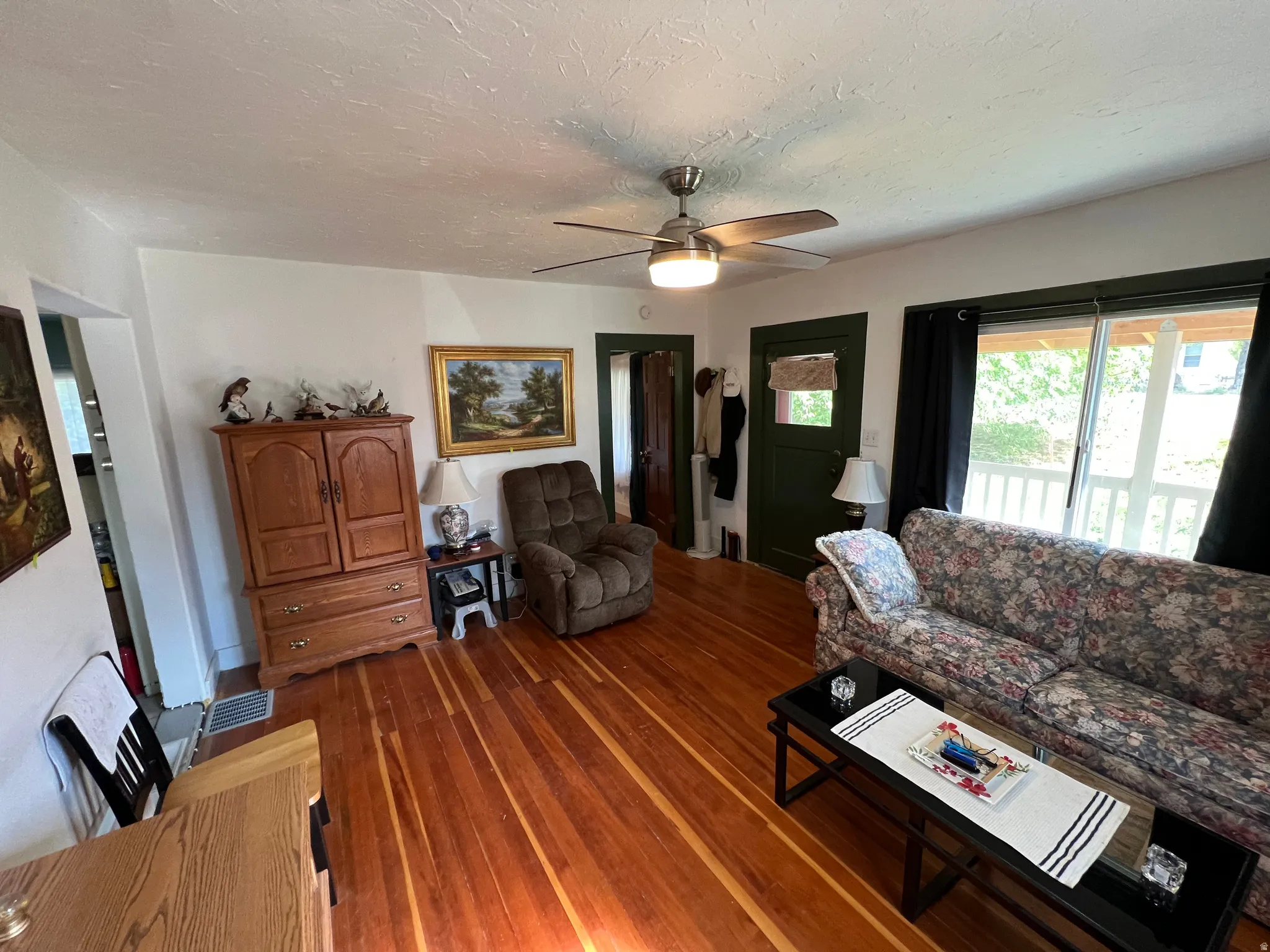 Living area featuring wood-finish flooring, a ceiling fan with integrated lighting, and white walls