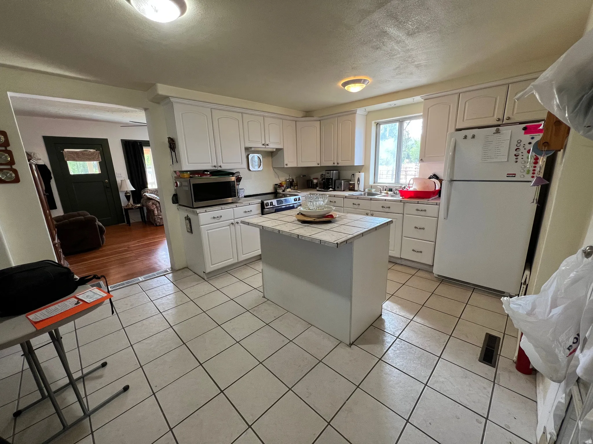Kitchen featuring white cabinetry, tile countertops, a center island with a tile surface, and tile flooring