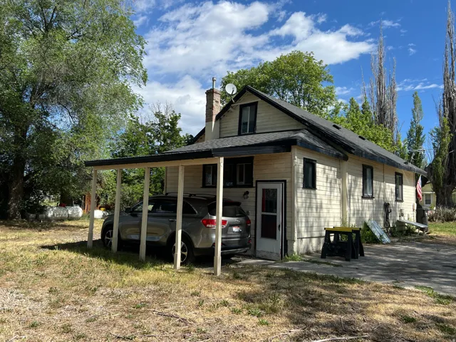 Exterior featuring light-colored siding, a dark shingled roof, and black window trim