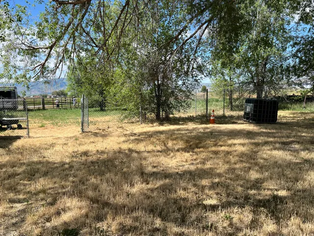 Expansive outdoor space featuring a chain-link fence, mature trees, and a mountain backdrop