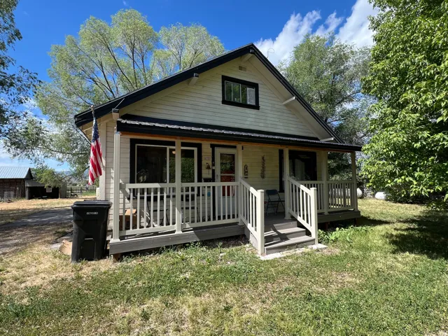 Gabled facade featuring light-colored siding, contrasting trim, and a covered porch