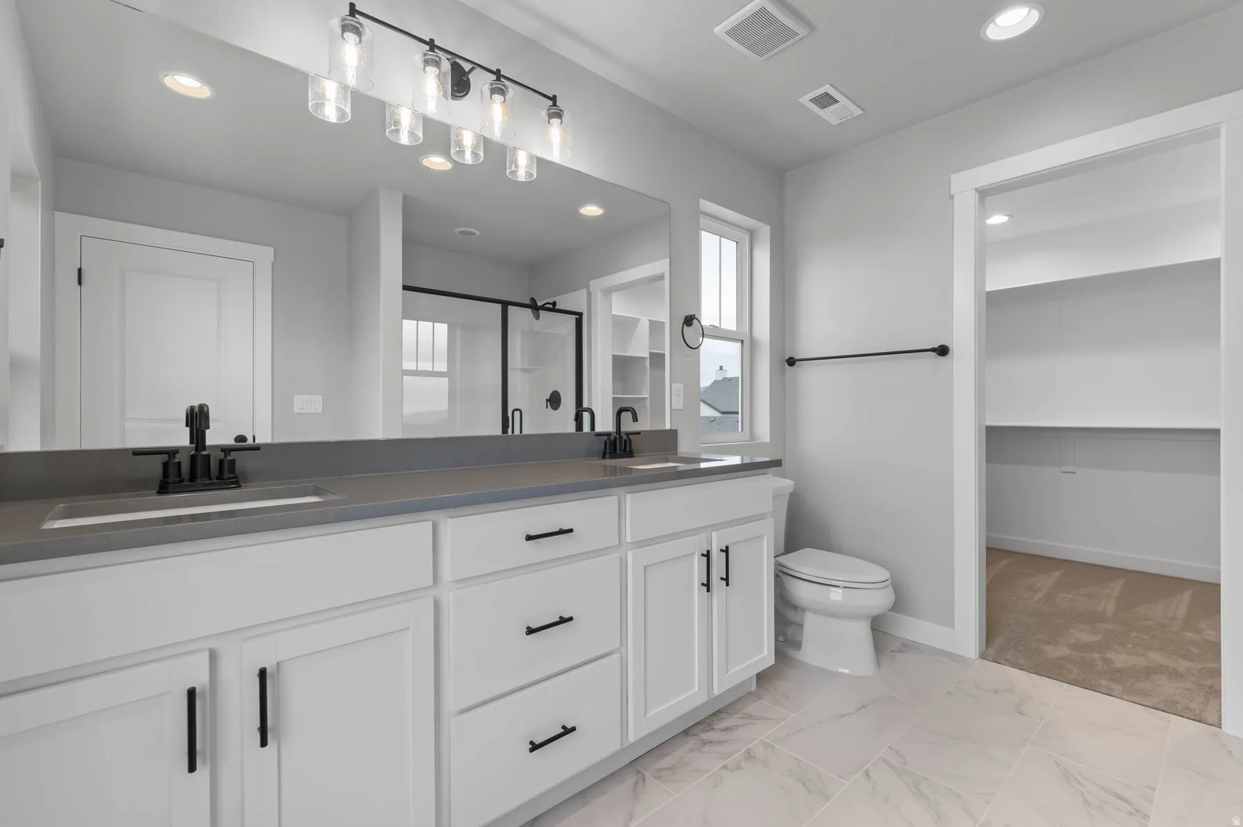 Double vanity with stone countertop and integrated sinks, matte black fixtures, and a six-light bar sconce