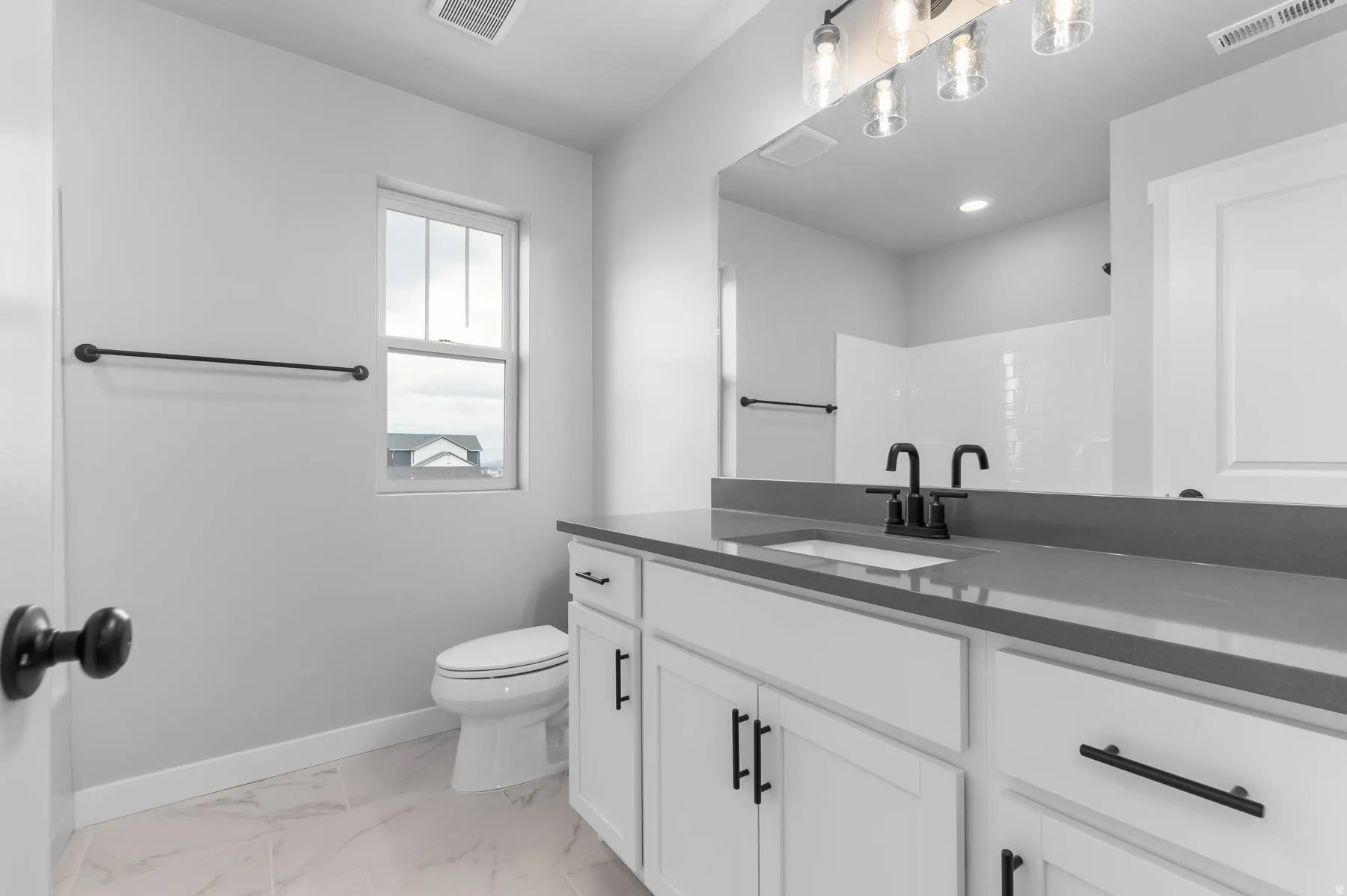 Bathroom featuring a white vanity with shaker-style cabinetry, matte black hardware, a grey stone-finish countertop, and a rectangular undermount sink